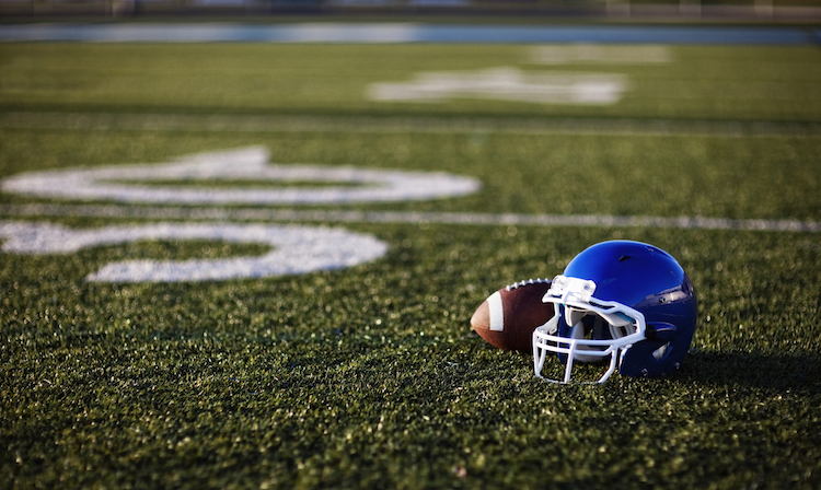 An American football helmet and football on the football field. Perfect image for your football announcement.